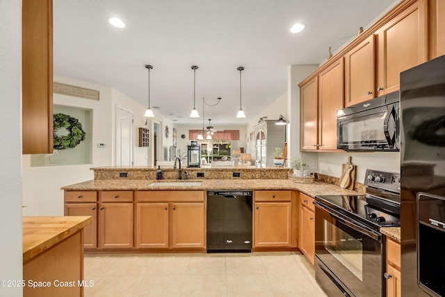 kitchen featuring a peninsula, a sink, hanging light fixtures, light stone countertops, and black appliances