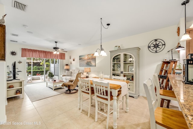 dining space featuring light tile patterned floors, visible vents, and ceiling fan with notable chandelier