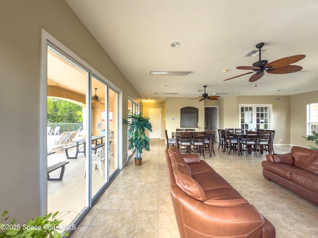 living area featuring a healthy amount of sunlight, light tile patterned floors, visible vents, and a ceiling fan