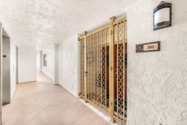 hallway with a textured ceiling and a textured wall