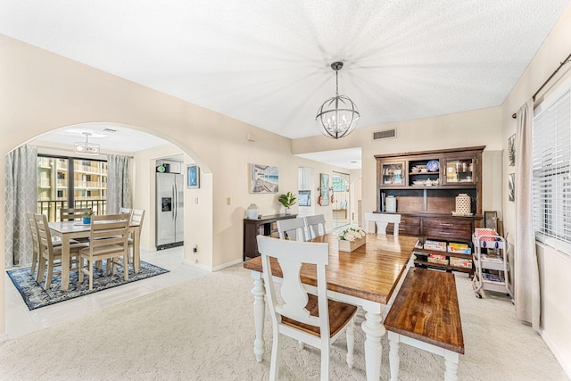 dining area featuring arched walkways, visible vents, light carpet, a chandelier, and baseboards