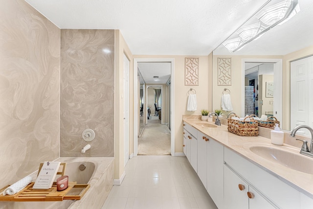 full bathroom featuring a textured ceiling, double vanity, a tub to relax in, and a sink