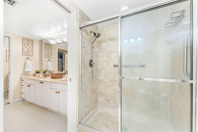 bathroom featuring a textured ceiling, a sink, visible vents, double vanity, and a stall shower