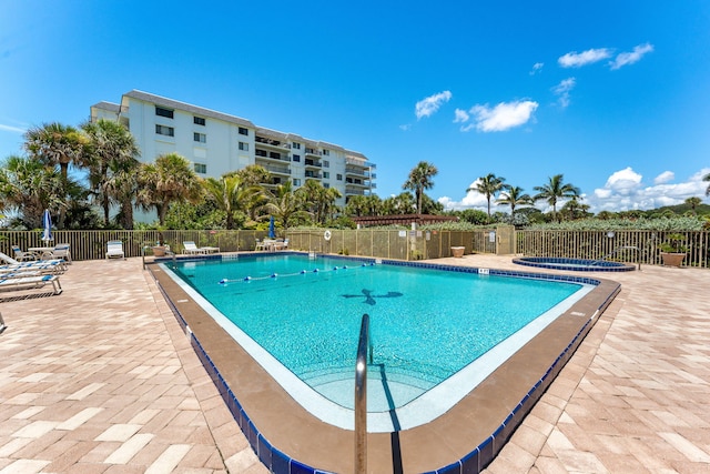 community pool featuring a community hot tub, a patio area, and fence