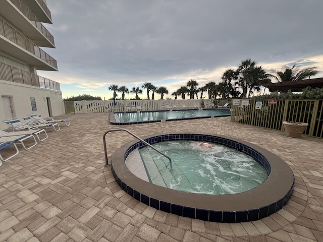 pool featuring a patio area, a hot tub, and fence