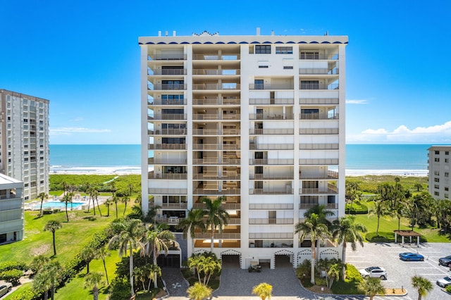 view of building exterior featuring a water view and a beach view