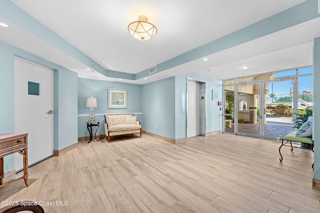 sitting room featuring recessed lighting, visible vents, baseboards, light wood finished floors, and elevator