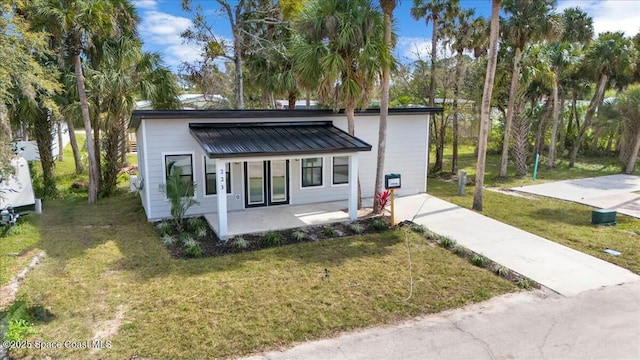 view of front facade with covered porch, metal roof, a front lawn, and a standing seam roof