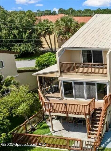 rear view of property with a balcony, fence, and stairway