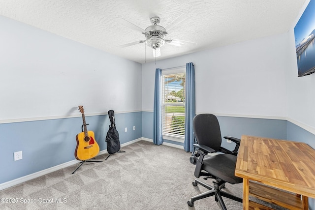 carpeted office space with a textured ceiling, baseboards, and ceiling fan