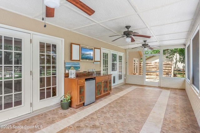 sunroom featuring french doors, ceiling fan, and a sink