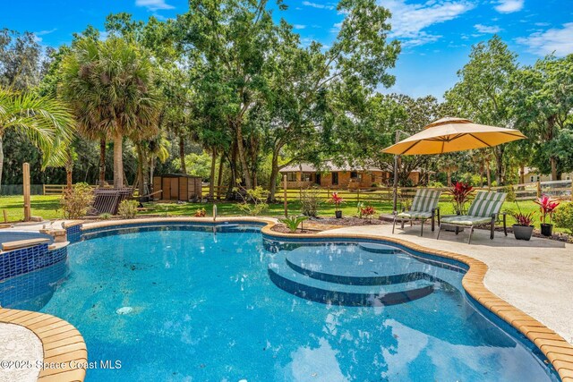 view of pool featuring a pool with connected hot tub, fence, and a patio