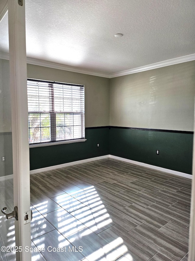 unfurnished room featuring a textured ceiling, baseboards, dark wood finished floors, and crown molding