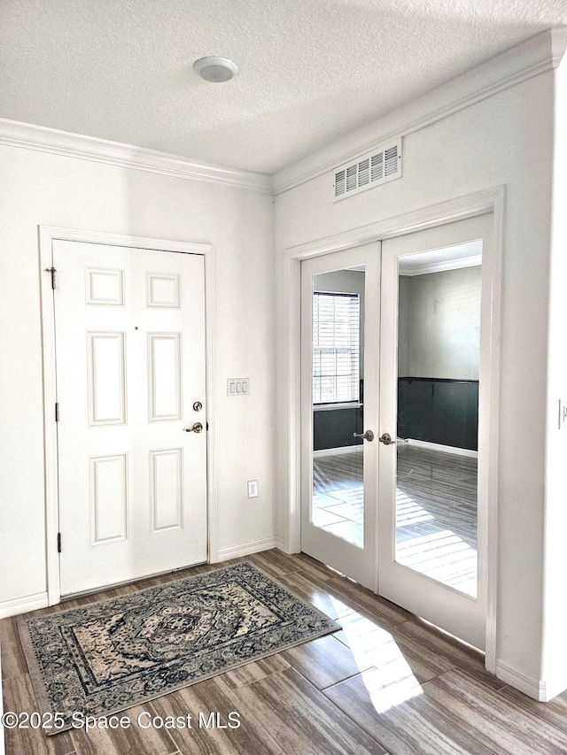 entryway featuring crown molding, visible vents, wood finished floors, and french doors