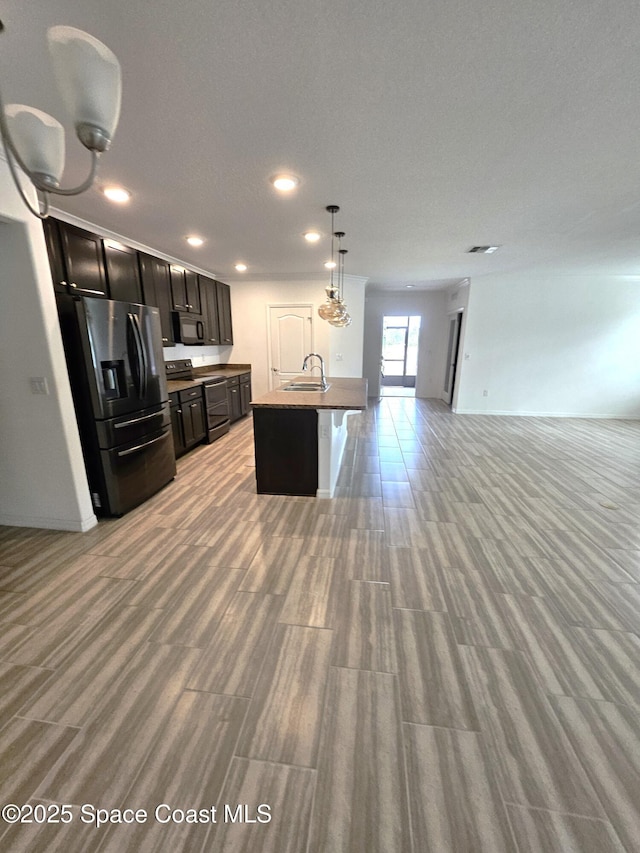 kitchen featuring decorative light fixtures, open floor plan, a kitchen island with sink, a sink, and black appliances