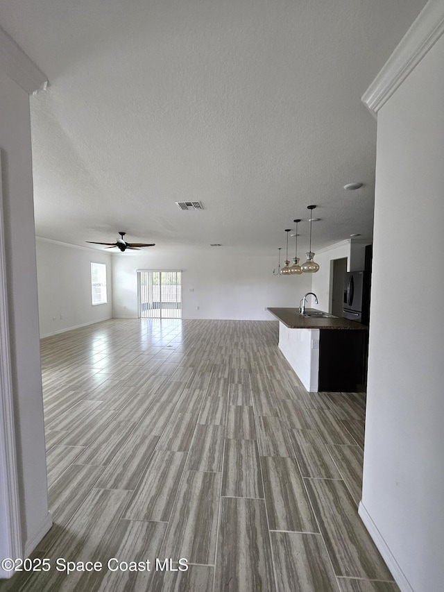 interior space with a textured ceiling, a sink, visible vents, and light wood-style floors