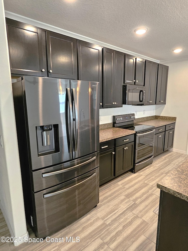 kitchen featuring stainless steel appliances, dark countertops, a textured ceiling, and recessed lighting