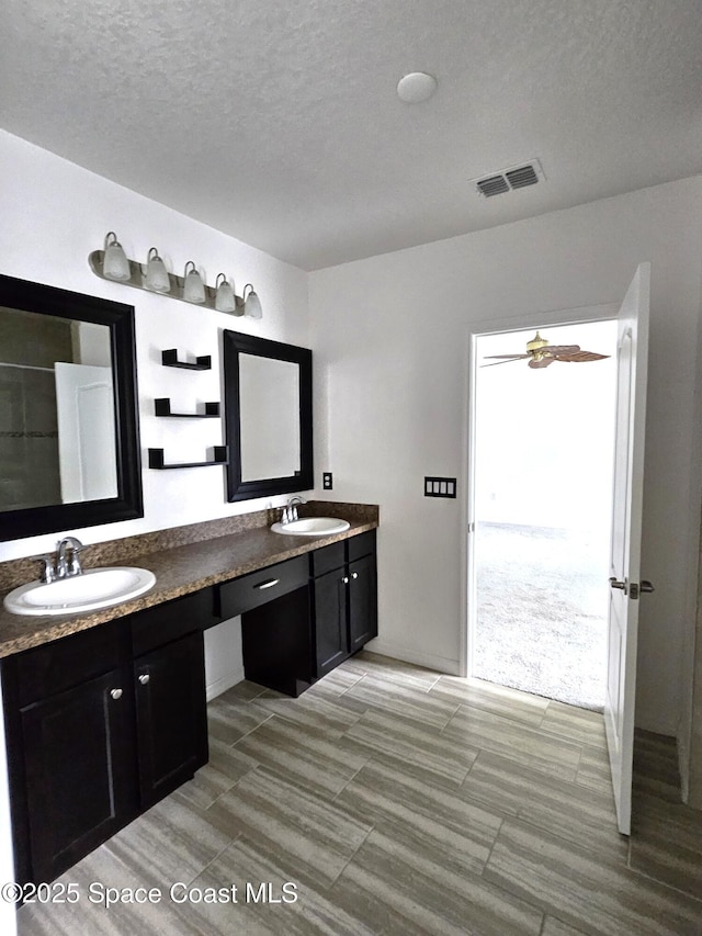 full bathroom with visible vents, a sink, a textured ceiling, and double vanity