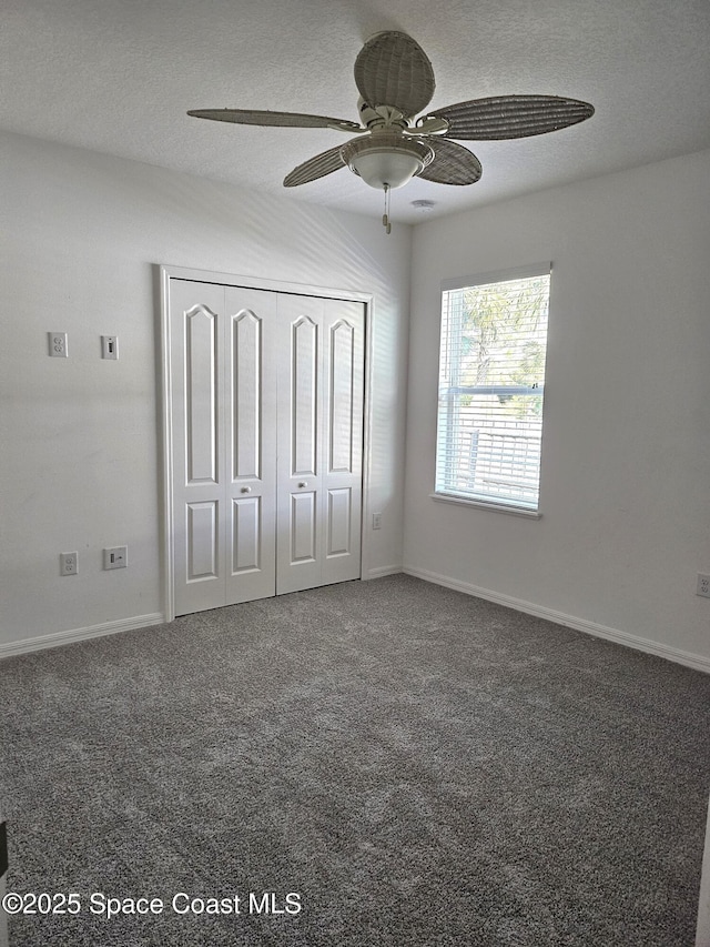 unfurnished bedroom featuring a textured ceiling, carpet flooring, a ceiling fan, baseboards, and a closet