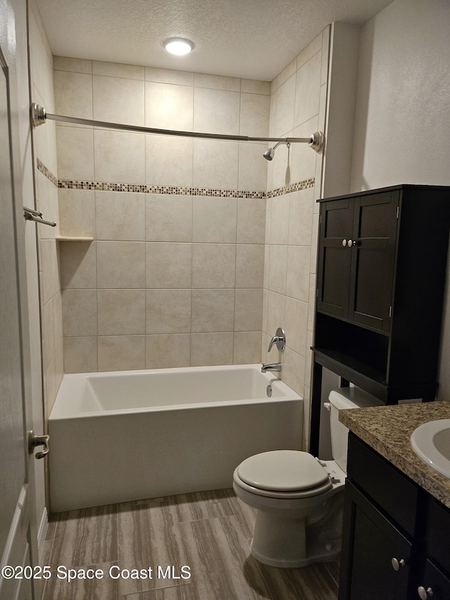 bathroom with shower / bathtub combination, a textured ceiling, toilet, and wood finished floors