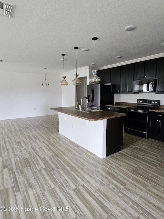 kitchen featuring a kitchen breakfast bar, dark cabinets, decorative light fixtures, a kitchen island with sink, and black appliances