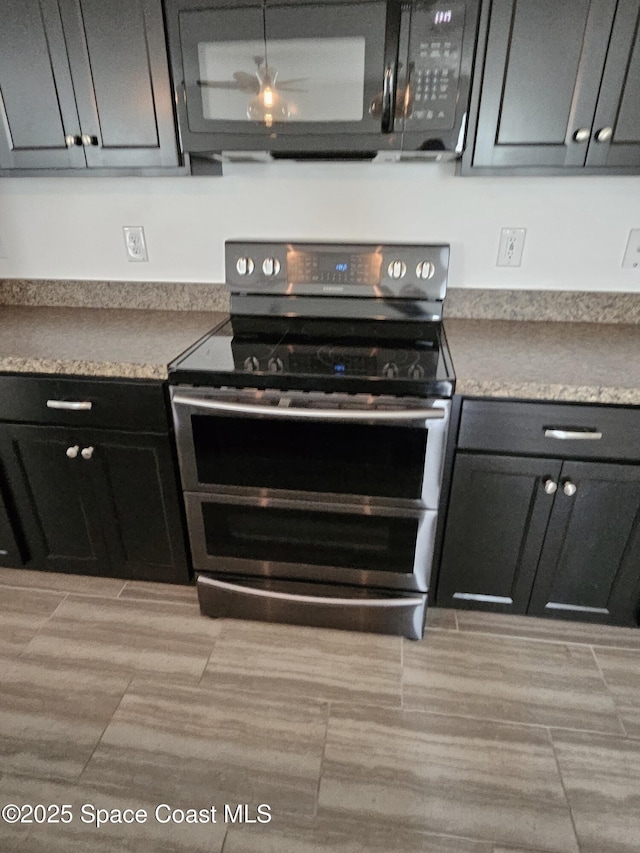 kitchen with black microwave, light countertops, range with two ovens, and dark cabinetry