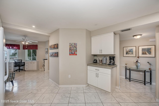 kitchen featuring marble finish floor, white cabinetry, visible vents, and baseboards