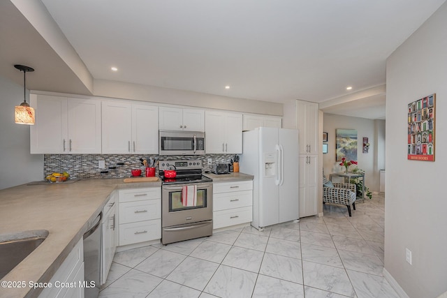 kitchen featuring decorative light fixtures, stainless steel appliances, light countertops, white cabinetry, and backsplash