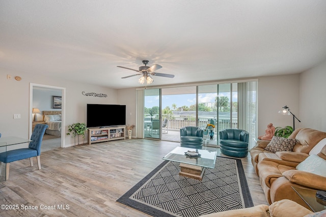 living area with light wood-type flooring, a ceiling fan, and floor to ceiling windows