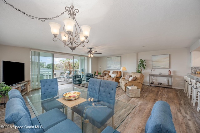 dining room with floor to ceiling windows, a textured ceiling, wood finished floors, baseboards, and ceiling fan with notable chandelier