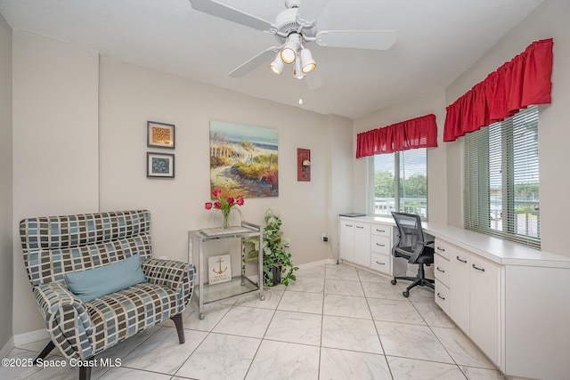 office area with ceiling fan and baseboards