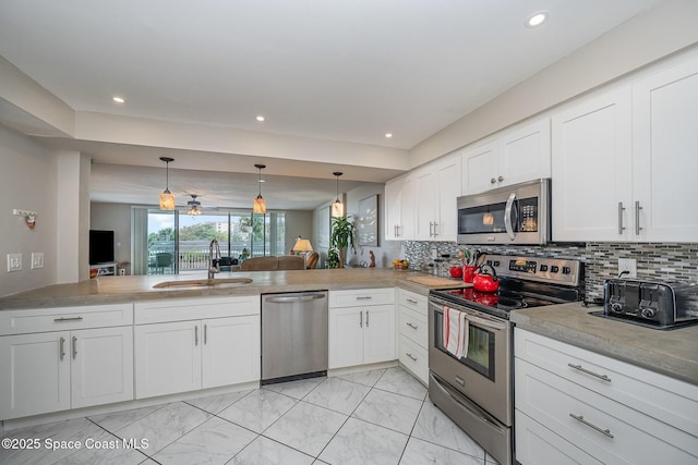 kitchen with stainless steel appliances, white cabinets, a sink, and decorative backsplash