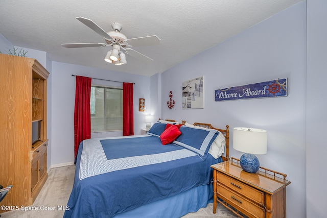 bedroom with baseboards, a ceiling fan, a textured ceiling, and light colored carpet