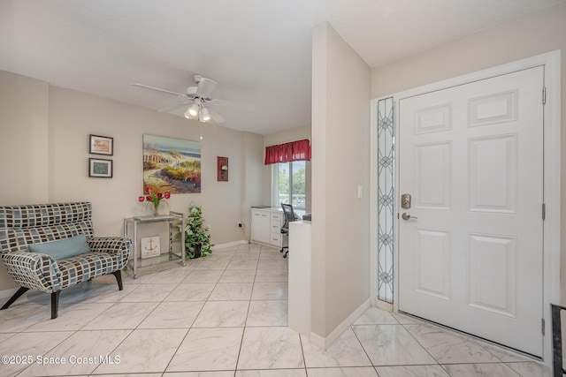 entryway with ceiling fan, marble finish floor, and baseboards