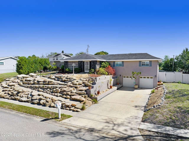 view of front of house with fence, driveway, an attached garage, and stucco siding