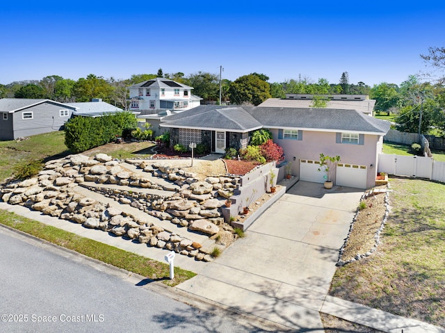 view of front of property with concrete driveway, fence, and an attached garage