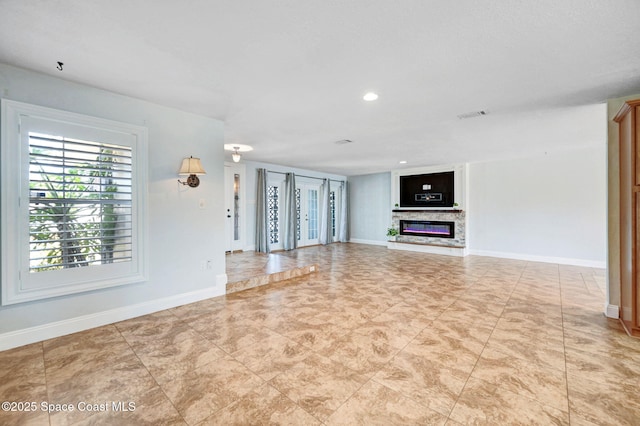 unfurnished living room with recessed lighting, a glass covered fireplace, visible vents, and baseboards