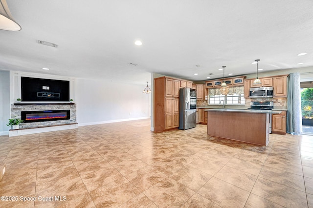 kitchen featuring stainless steel appliances, tasteful backsplash, open floor plan, a kitchen island, and a stone fireplace