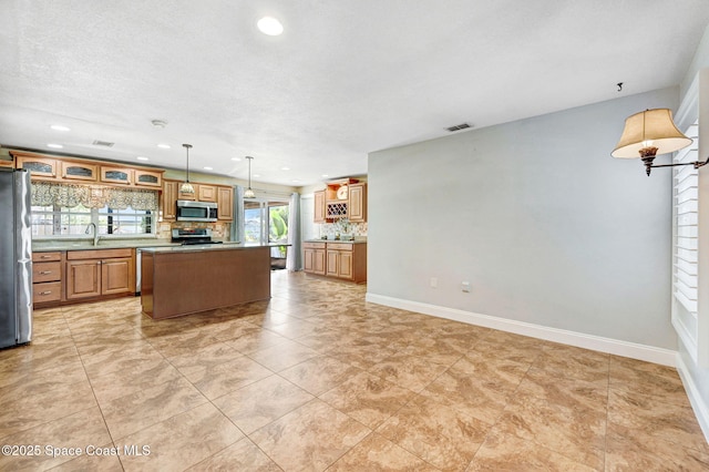 kitchen with a center island, stainless steel appliances, visible vents, decorative backsplash, and baseboards