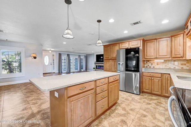 kitchen with visible vents, stainless steel fridge with ice dispenser, a kitchen island, backsplash, and range with electric stovetop