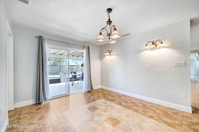 unfurnished room featuring a notable chandelier, baseboards, and a textured ceiling