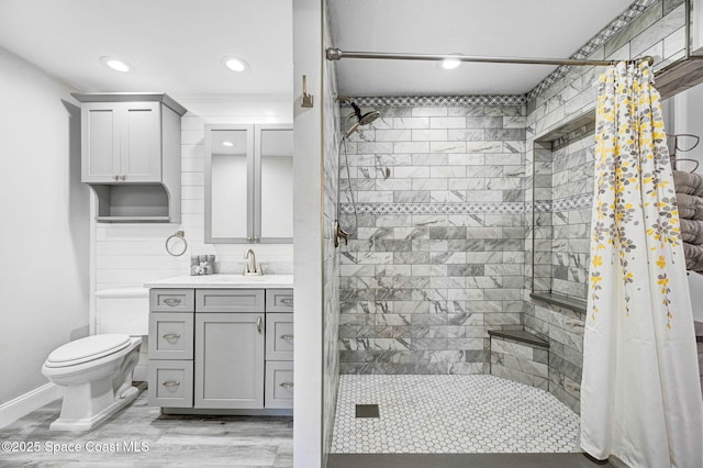 bathroom featuring wood finished floors, a stall shower, vanity, and toilet