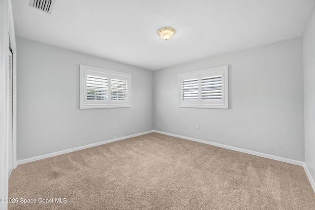 unfurnished room with carpet, visible vents, and baseboards