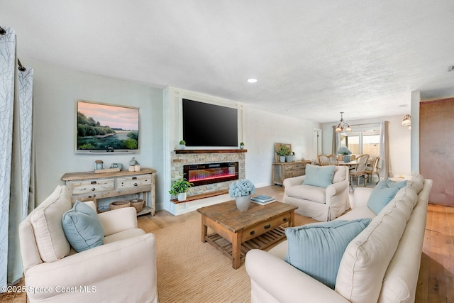 living area featuring light wood-style floors, a fireplace, a chandelier, and recessed lighting