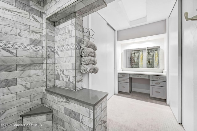 bathroom featuring a tile shower and vanity