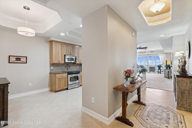 kitchen featuring light tile patterned floors, a tray ceiling, backsplash, and stainless steel appliances