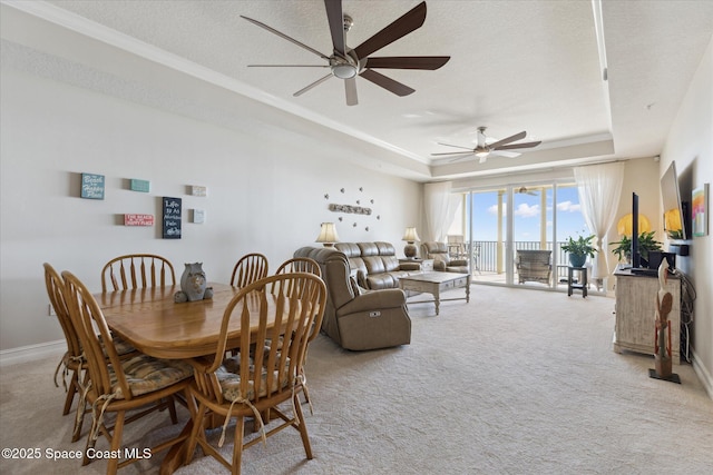 dining room with baseboards, a tray ceiling, carpet flooring, a textured ceiling, and a ceiling fan