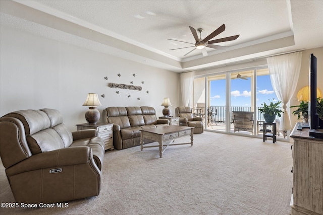 living room featuring a textured ceiling, carpet, a raised ceiling, and ceiling fan