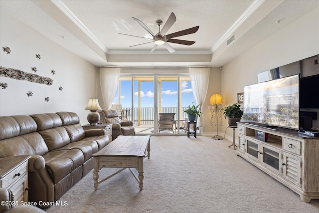 living area featuring visible vents, a ceiling fan, carpet flooring, crown molding, and a raised ceiling