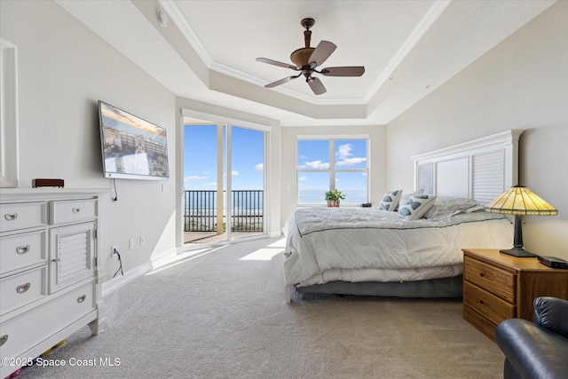 bedroom featuring a ceiling fan, a tray ceiling, access to exterior, crown molding, and carpet flooring